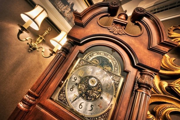 "Howard Miller Grandfather Clock - A masterfully crafted, elegant timepiece featuring a polished wooden case, intricate brass dial with Roman numerals, and a swinging pendulum, symbolizing timeless craftsmanship and sophisticated design.