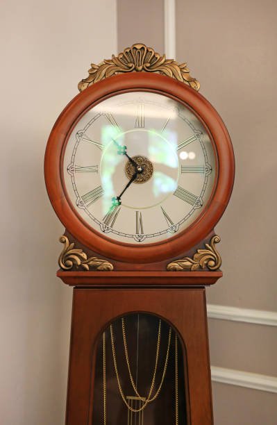 “Tall Ridgeway Grandfather Clock in rich cherry wood with an arched bonnet top, brass moon-phase dial, three polished brass weights, and a swinging brass pendulum visible through beveled glass panels.”